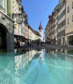 People in swimming pool against buildings in city