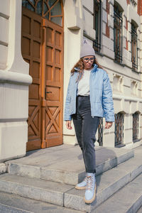 Portrait of young man standing against building