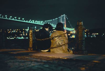 Rear view of people sitting at illuminated temple at night