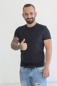 Portrait of young man standing against white background