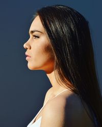 Side view of young woman against black background