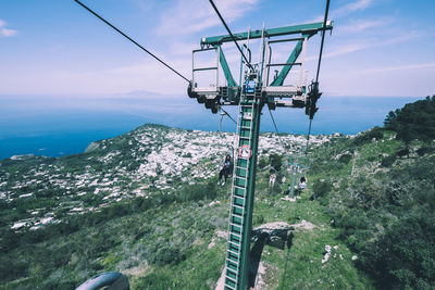 Overhead cable car over sea against sky