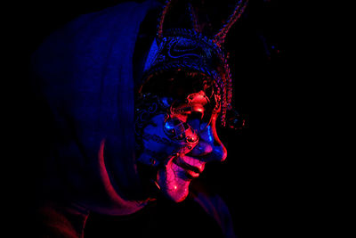 Portrait of man wearing mask against black background