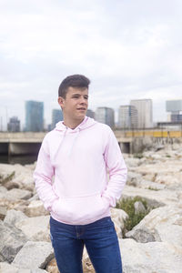 Young man standing in city against sky