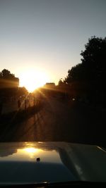 Road amidst silhouette trees against sky during sunset