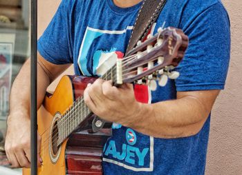 Midsection of man playing guitar