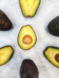 Fresh avocado with herbs and lemons lies on the table on white background. flat lay. top view.