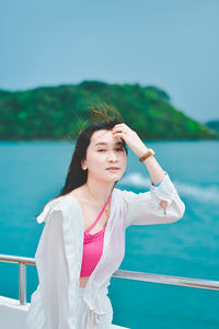 Young woman standing against blue sky