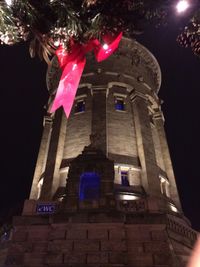 Low angle view of illuminated cross at night