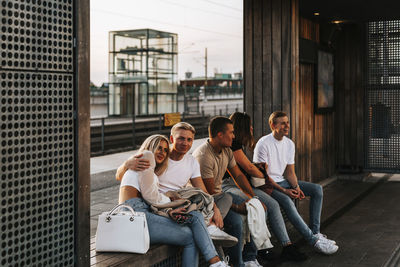 Smiling friends sitting on bench together