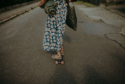 Low section of woman riding skateboard on road