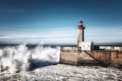 Lighthouse by sea against sky