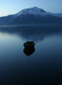 Scenic view of lake by snowcapped mountains against sky