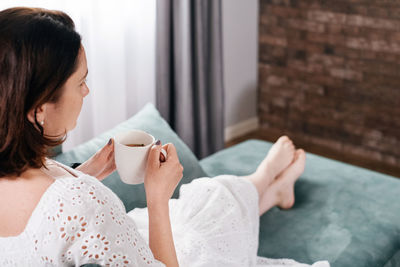 Woman drinking mug of coffee in cozy home atmosphere in the morning. real middle age plus size