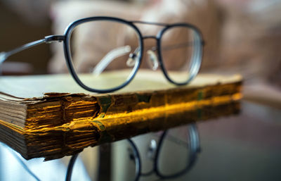 Eye glasses or spectacles kept on top of a really old torn and partially damaged religious book