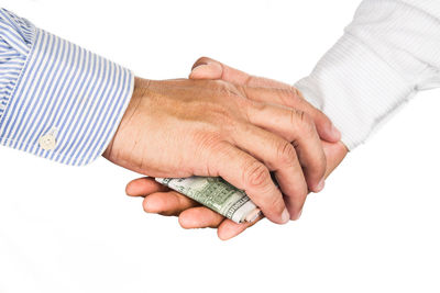 Close-up of hand holding paper over white background