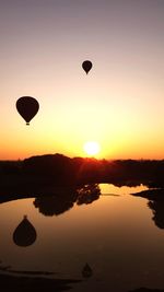 Silhouette hot air balloon flying against sky during sunset