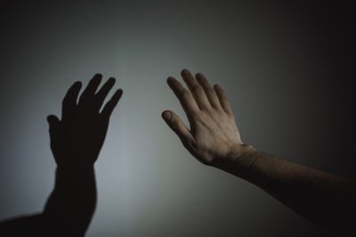 Cropped hand of person reaching wall