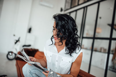 Woman reading book while sitting in office