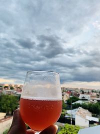 Close-up of hand holding drink against sky