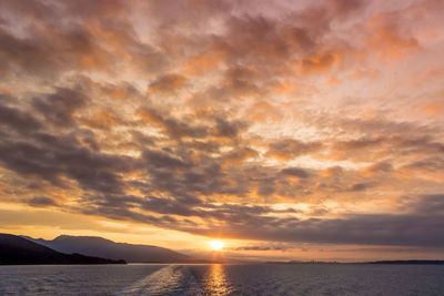 Scenic view of sea against dramatic sky during sunset