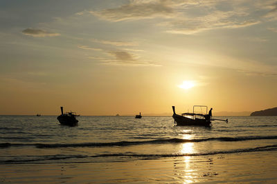 Silhouette boats in sea against sky during sunset