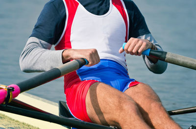 Midsection of athlete rowing on sea