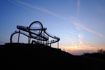 Low angle view of silhouette rollercoaster against sky during sunset