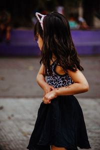 Cute girl looking away while standing on road against sky