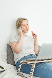 Young woman using mobile phone while sitting on sofa at home