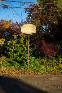 Road sign by trees against sky