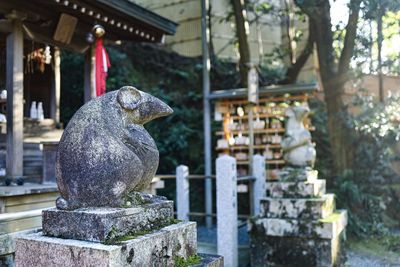 View of statue against stone wall in kyoto shrine.