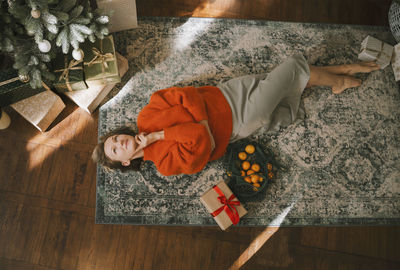 Contemplative woman lying on carpet at home