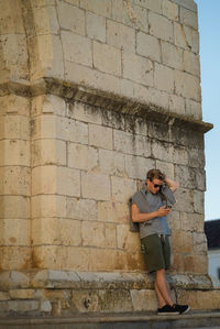 Low angle view of young man standing by wall