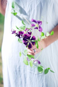 Midsection of woman holding purple flowers