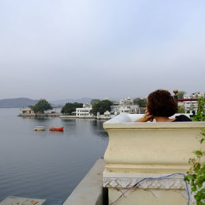 Rear view of woman sitting on boat against sky