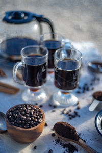 Still life with glass mugs of black hot coffee, coffee beans, coffee at home