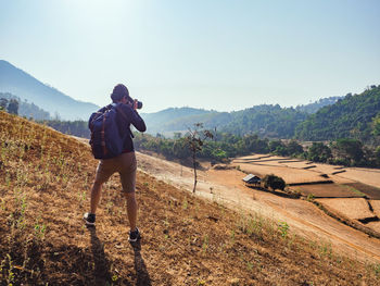 Hiker photographing golden rice terraces after the harvest season.