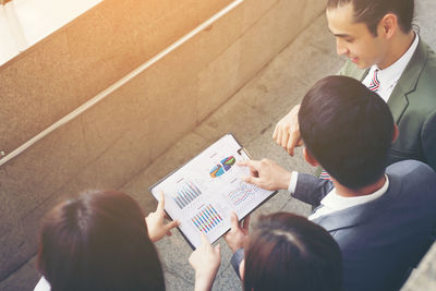 High angle view of colleagues analyzing data while standing on elevated walkway 