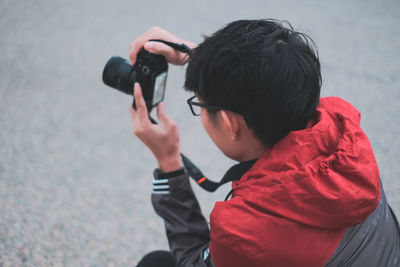 High angle view of man photographing while crouching on road