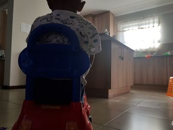 Rear view of man standing against wall at home