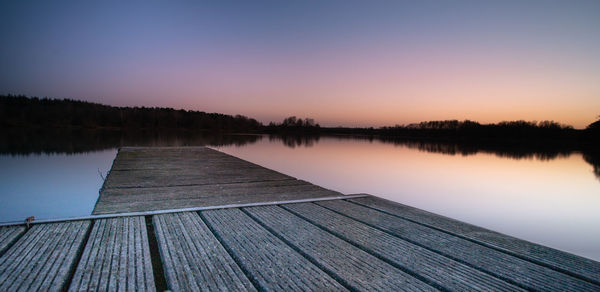 Pier over lake against sky during sunset