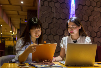 Businesswomen discussing business strategy while sitting in restaurant