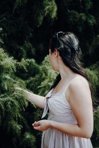 Side view of woman standing by trees