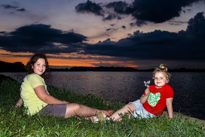 Full length of woman sitting on land against sky during sunset