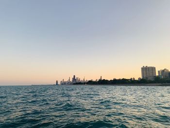 Scenic view of sea and buildings against clear sky