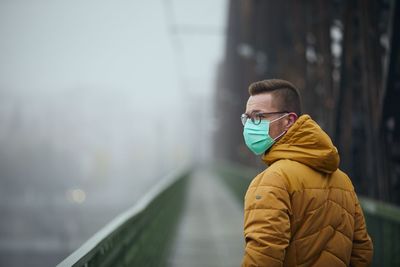 Rear view of man wearing mask standing on footbridge