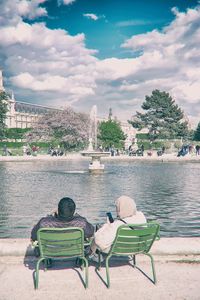 Chairs sitting on chair by river against sky