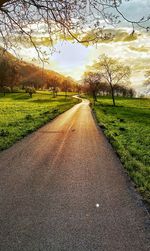 Empty road amidst field against sky