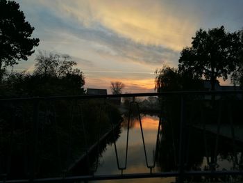 Reflection of silhouette trees in water against sky